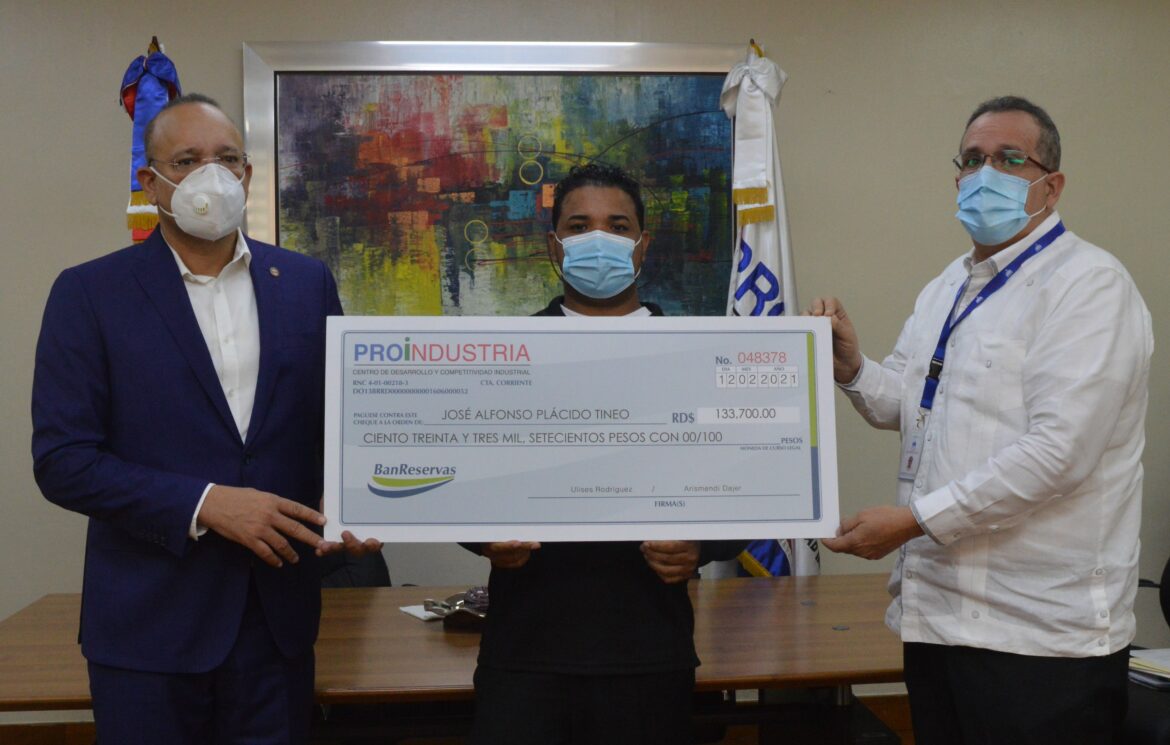 Ulises Rodríguez en compañía del director Administrativo y Financiero, Arismedy Dajer entrega el cheque a José Plácido