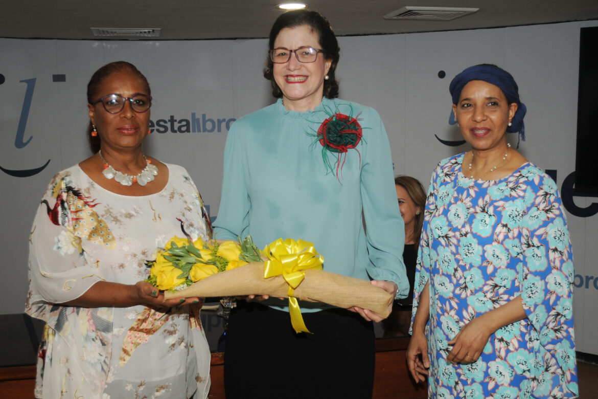 12.- Nurys Veras y Fiona Almonte de Domínguez entregan un arreglo de flores a la invitada Aura Celeste Fernández.