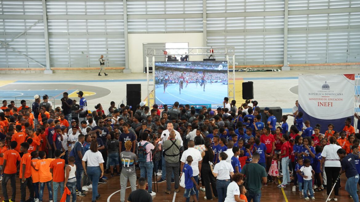 PIE DE FOTO 1 ALBERTO RODRÍGUEZ MELLA rodeado de estudiantes durante la transmisión de la carrera de los 400 metros femeninos que ganó Marileidy Paulino